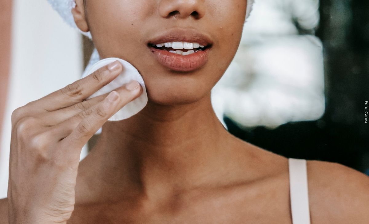 Foto de una mujer limpiando su rostro con un pomo de algodón
