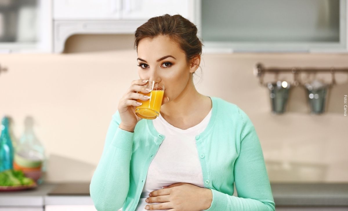 Foto de una mujer bebiendo un vaso con jugo de naranja