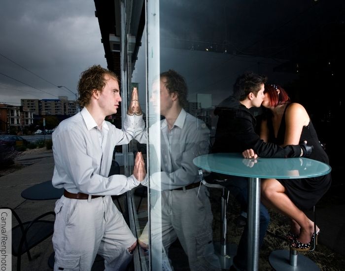 Foto de un hombre viendo como su novia lo engaña con otro hombre a través de una ventana