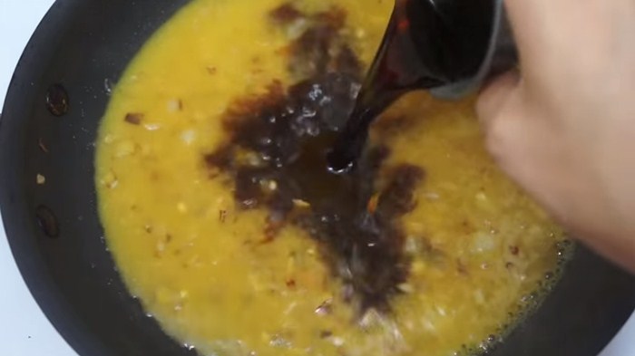 Foto de cebolla picada, jugo de naranja con un chorro de salsa soya en un sartén