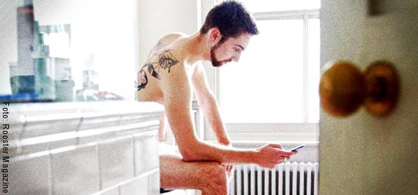 Foto de un hombre con el celular en el baño