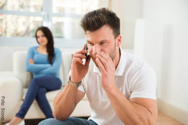 Foto de un hombre hablando por teléfono frente a su mujer