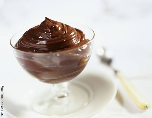 Foto de un pudín de chocolate servido en copa de vidrio sobre un plato blanco