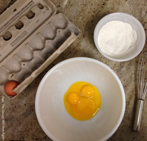 Foto de tres yemas de huevo en un plato hondo y azúcar en un recipiente blanco