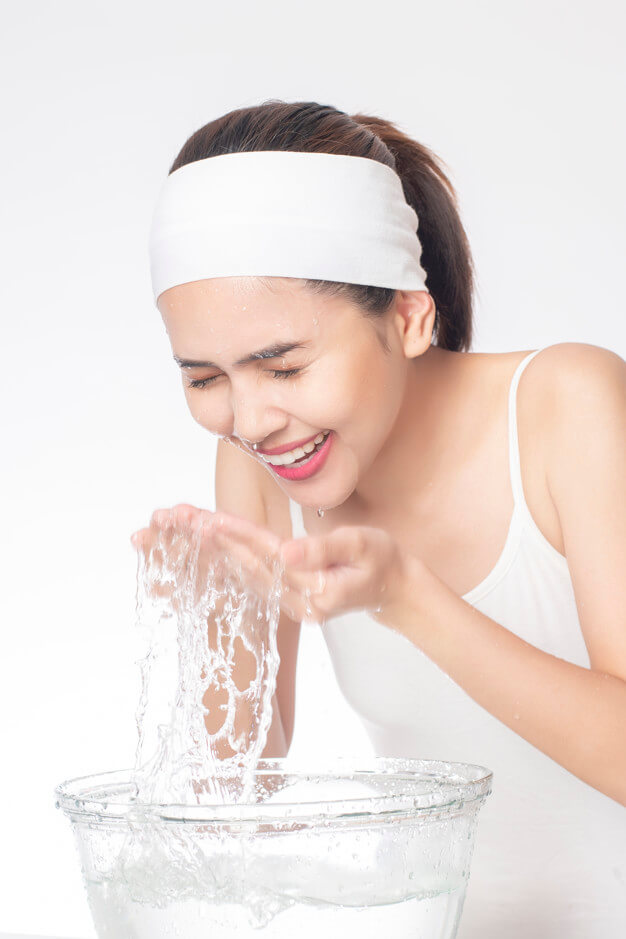 Foto de una chica lavándose el rostro con agua