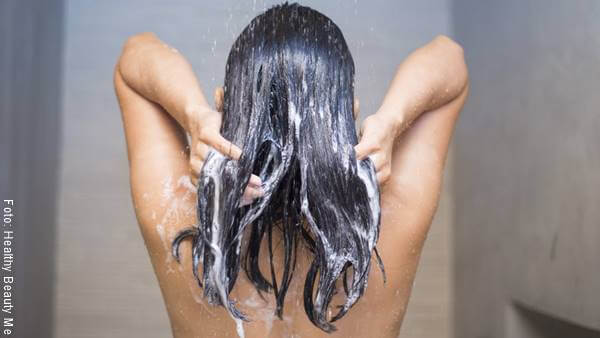Foto de una mujer lavándose el pelo luego de aplicar mascarilla