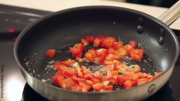 Foto de cuadritos de pimentón y cebolla en un sartén con aceite