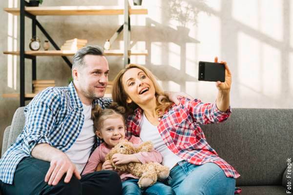 Foto de una pareja con su hija tomándose una selfie