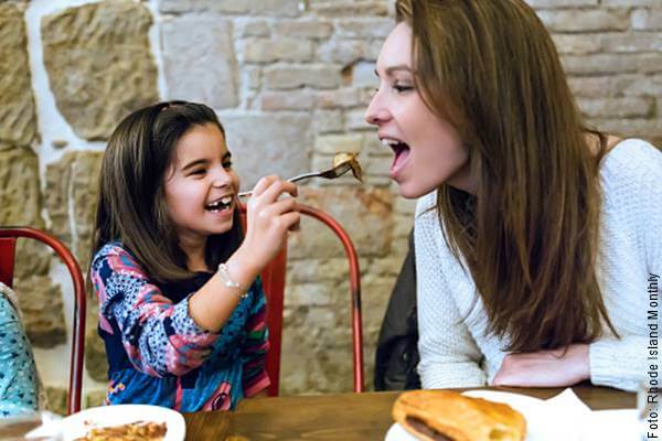 Foto de una niña dándole un bocado de cena a su mamá