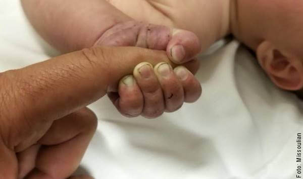 Foto de el dedo de un adulto agarrado por la mano de un bebé