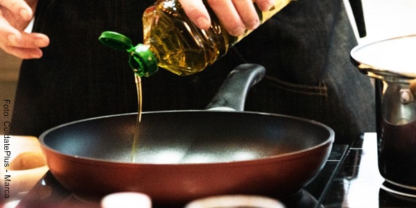 Foto de las manos de una persona añadiendo aceite de oliva en un sartén