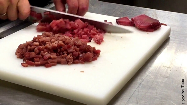 Foto de las manos de una persona cortando con un cuchillo un filete de atún