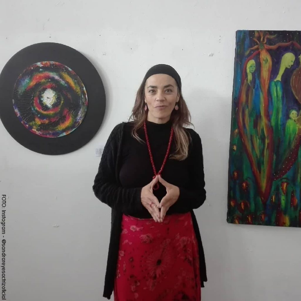 Sandra Reyes posando al lado de sus obras de arte