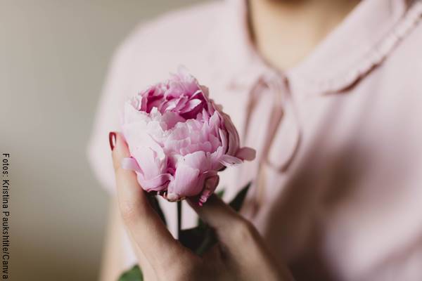 Foto de una mujer con una flor entre las manos
