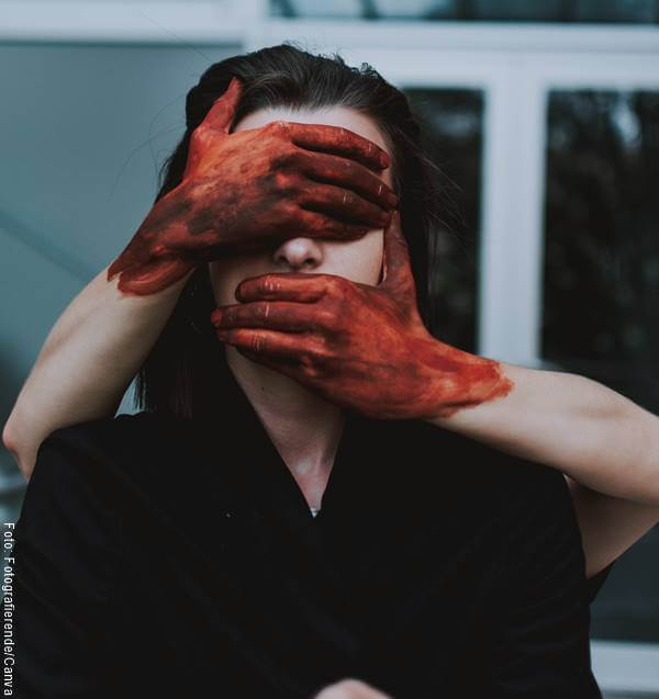Foto de una mujer a la que le están tapando los ojos y la boca con manos ensangrentadas
