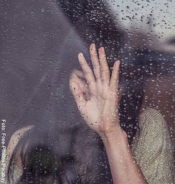 Foto de una mujer llorando recostada en la ventana