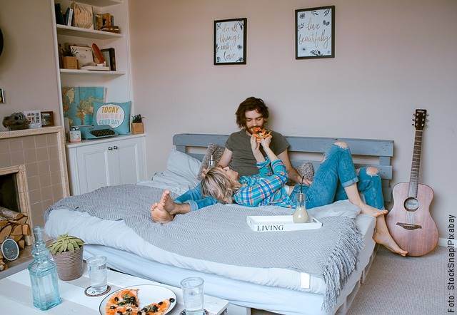 Foto de pareja en la cama comiendo