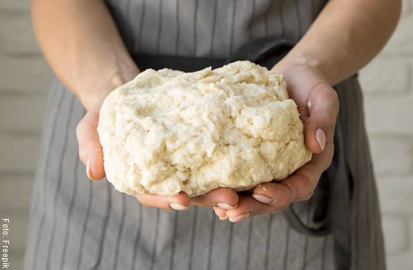 Foto de una mujer con masa de pan en las manos para preparar pan focaccia de cebolla