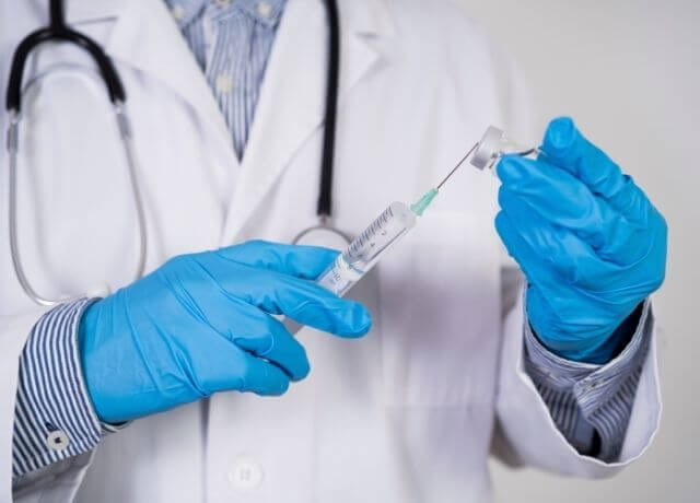 Foto de un médico con una vacuna entre sus manos