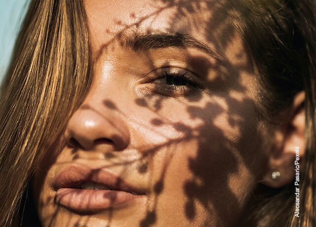 Foto de mujer con sombras de un árbol en su rostro