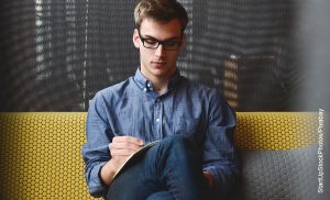 Foto de un hombre sentado en un sillón escribiendo
