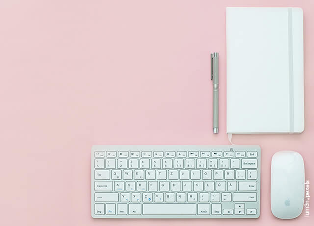 Foto del teclado de un computador sobre una mesa rosada