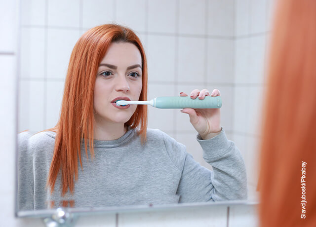 Foto de una mujer cepillándose los dientes