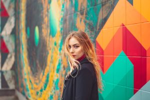 Foto de una mujer rubia posando frente a un mural de colores