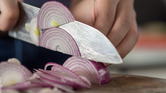 Foto de una persona cortando cebolla en julianas