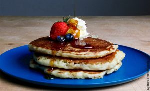 Foto de un plato de pancakes con fruta, crema y miel