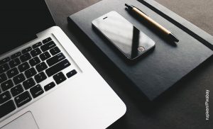Foto de una computador y un celular sobre un escritorio