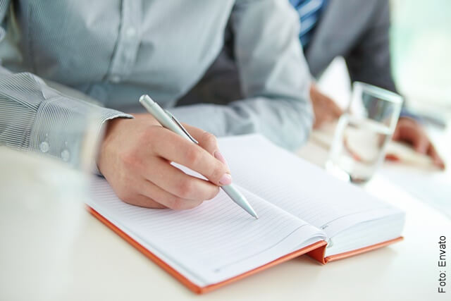 Foto de un hombre a punto de escribir en una agenda con un lapicero