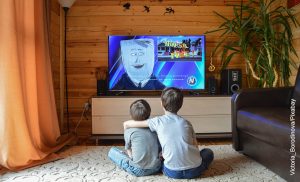 Foto de dos niños abrazados viendo televisión que muestra las caricaturas de los 90