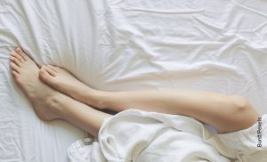 Foto de las piernas de una mujer sobre su cama que muestra cómo hacer cera casera