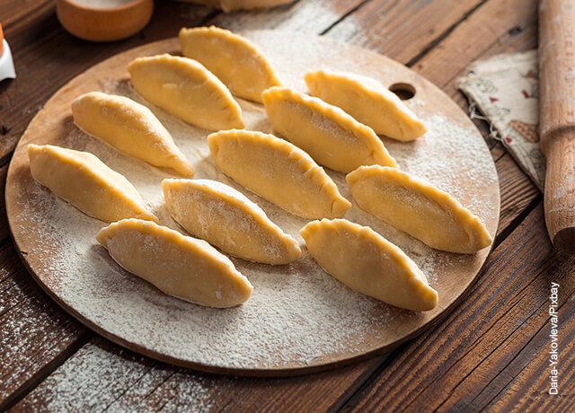Foto de empanadas crudas sobre un plato de madera