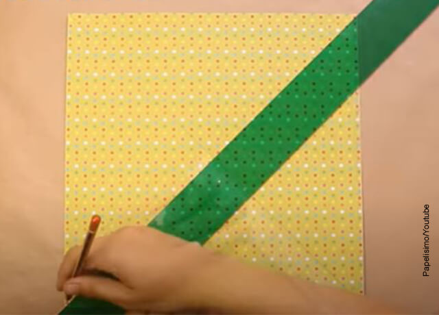 Foto de una mano trazando una línea sobre papel de colores