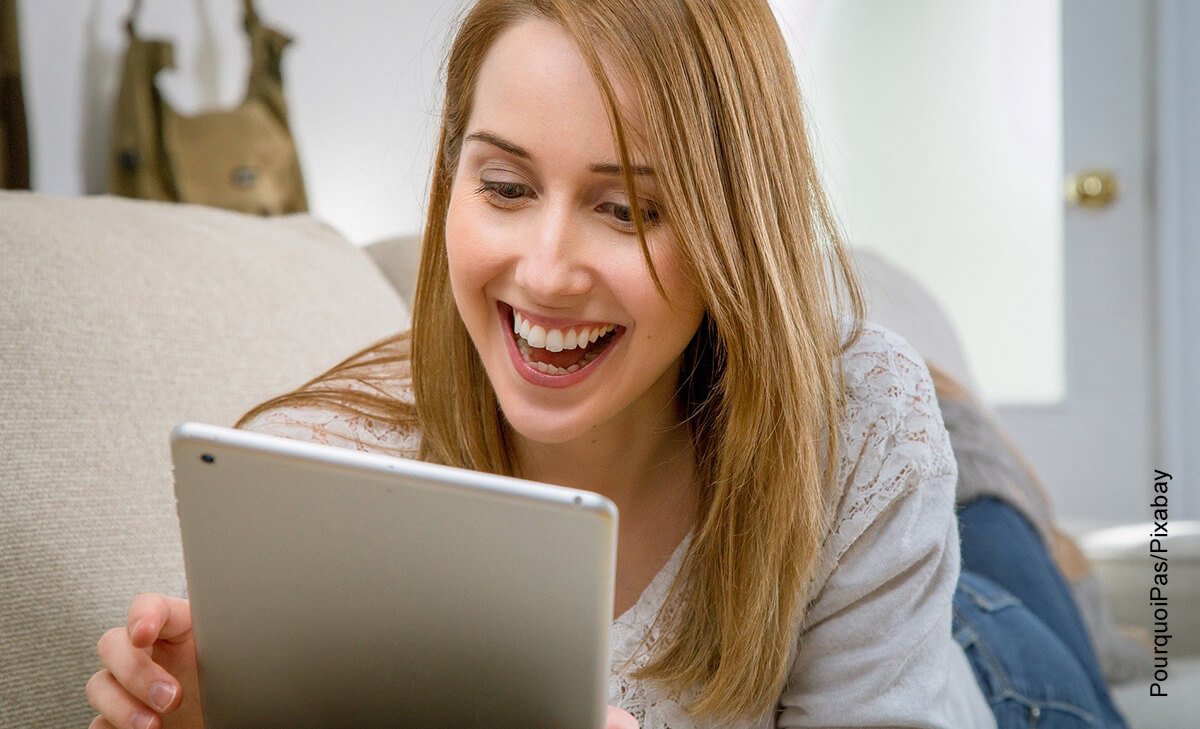 Foto de una mujer sonriendo frente a una tablet que ilustra cómo hacer una carta de petición