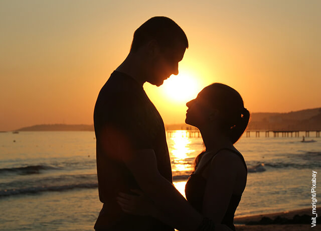 Foto de una pareja mirándose a los ojos en la playa en medio del atardecer