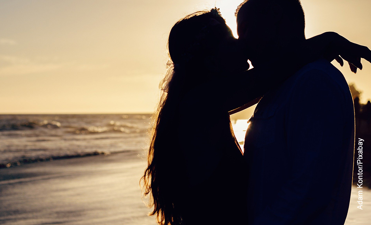 Foto de una pareja besándose en la playa que ilustra las frases para amantes