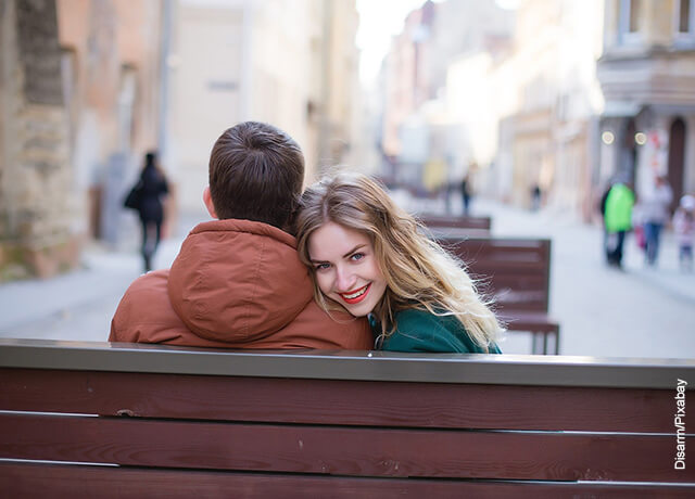 Foto de una pareja de novios sentados en una banca sonriendo