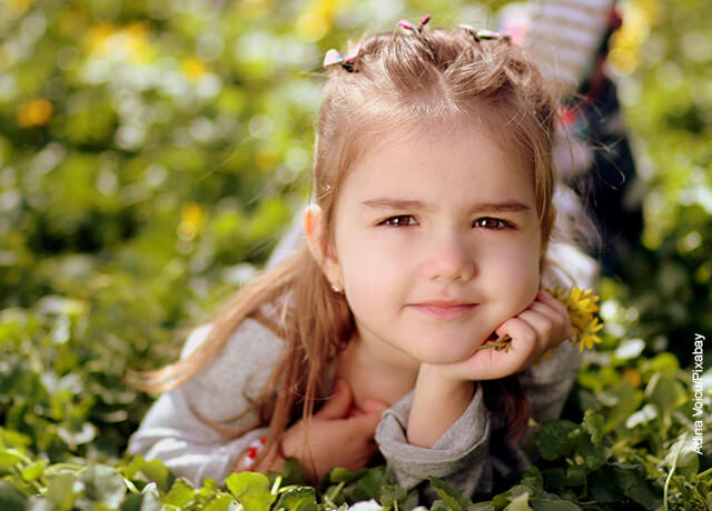 Foto de una niña recostada sobre el pasto