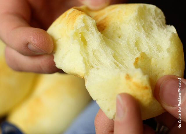 Foto de unas manos partiendo un pan de yuca por la mitad