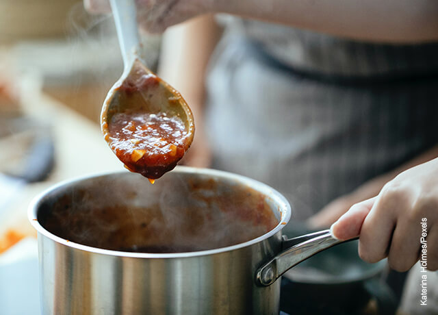 Foto de una cuchara de palo con salsa sobre una olla
