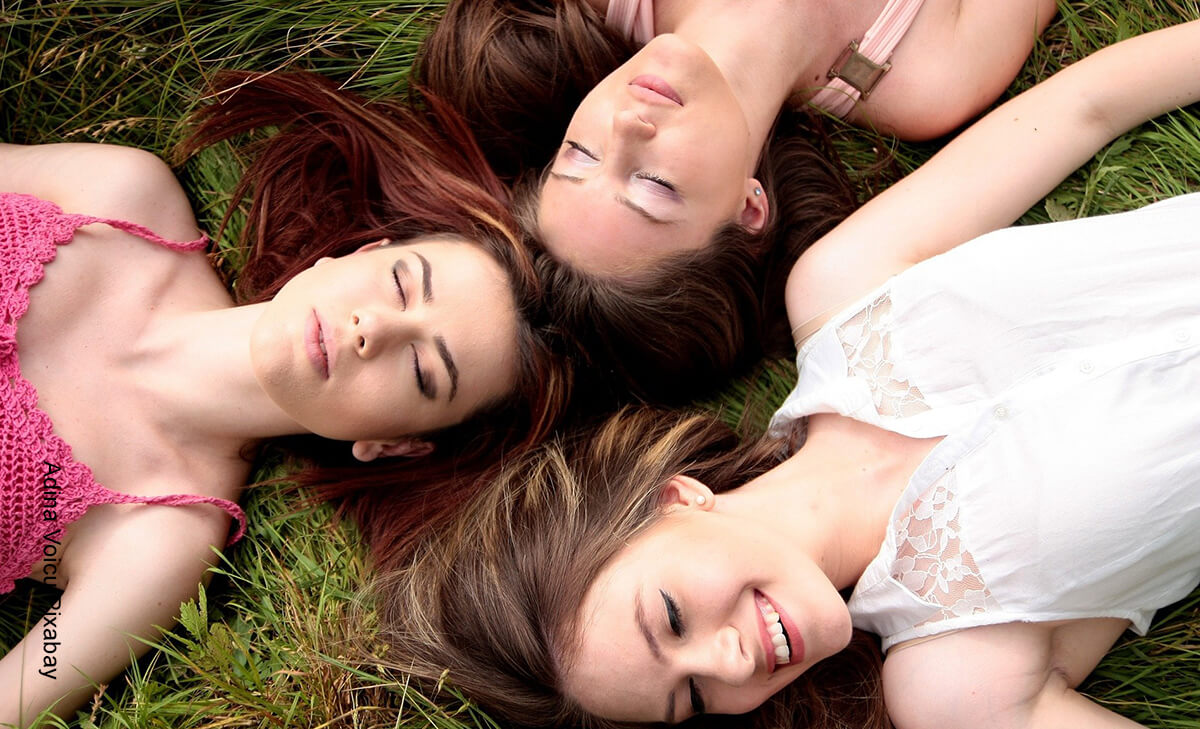 Foto de tres mujeres descansando sobre el pasto que ilustra lo que es soñar con amigos
