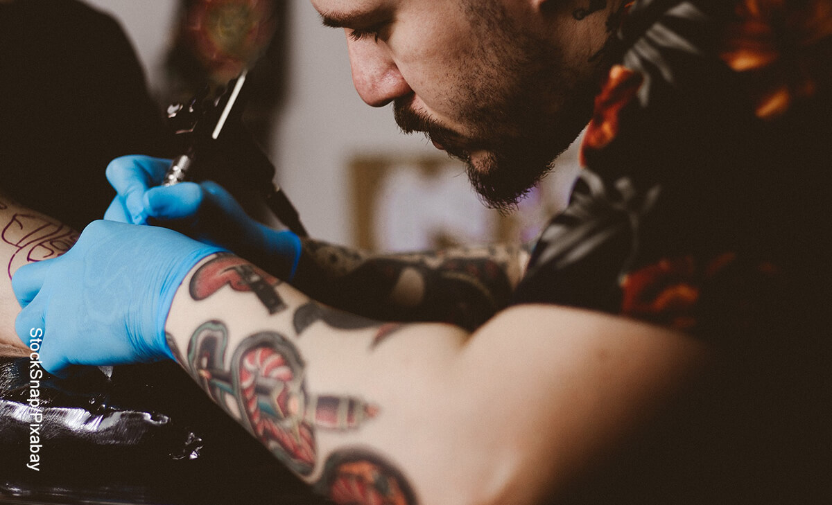 Foto de un tatuador trabajando en la piel que muestra los tatuajes de alas de ángel