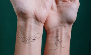 Foto de dos personas mostrando las manos que ilustra los tatuajes en la muñeca