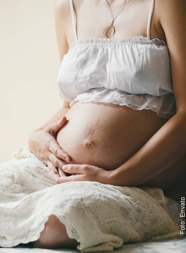 Foto del vientre de una mujer embarazada con ropa blanca ligera