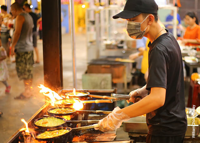Foto de un hombre sofriendo comida en sartenes que ilustra los camarones al ajillo y su receta