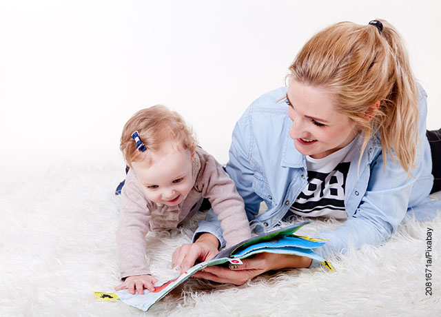 Foto de una mamá que juega con su hija con un libro