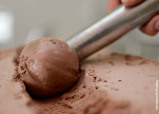 Foto de una persona sacando una bola de helado de chocolate de su recipiente